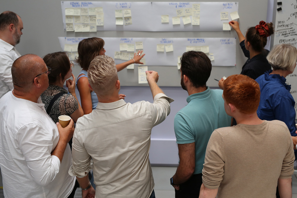 Team collaborating, placing sticky notes on a wall for brainstorming session.